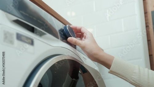 Close-up woman hand pushing washing machine buttons for setting program or start laundry  , health care lifestyle concept