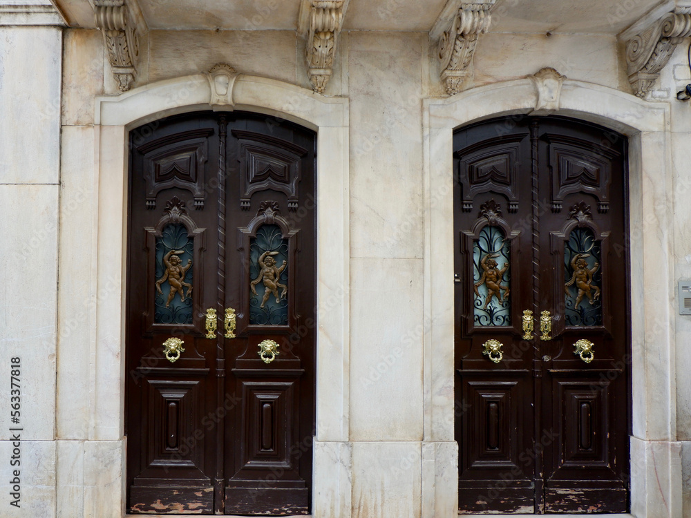 Two vintage double doors decorated with classy art deco ornate outside on the street of Elvas, Portugal