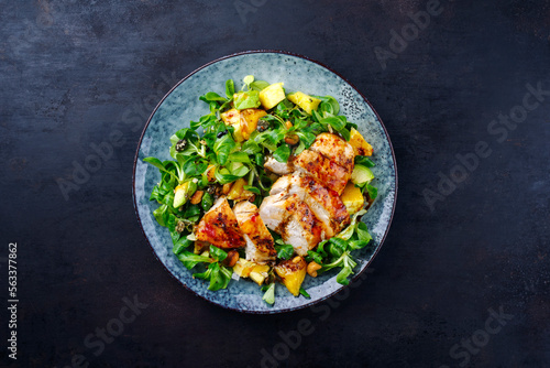 Traditional German lamb’s lettuce with chicken breast, fruit and cashew nuts served with spicy sweet and sour sauce as top view on a Nordic Design plate with copy space