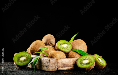 Ripe kiwi with leaves on a wooden tray. 