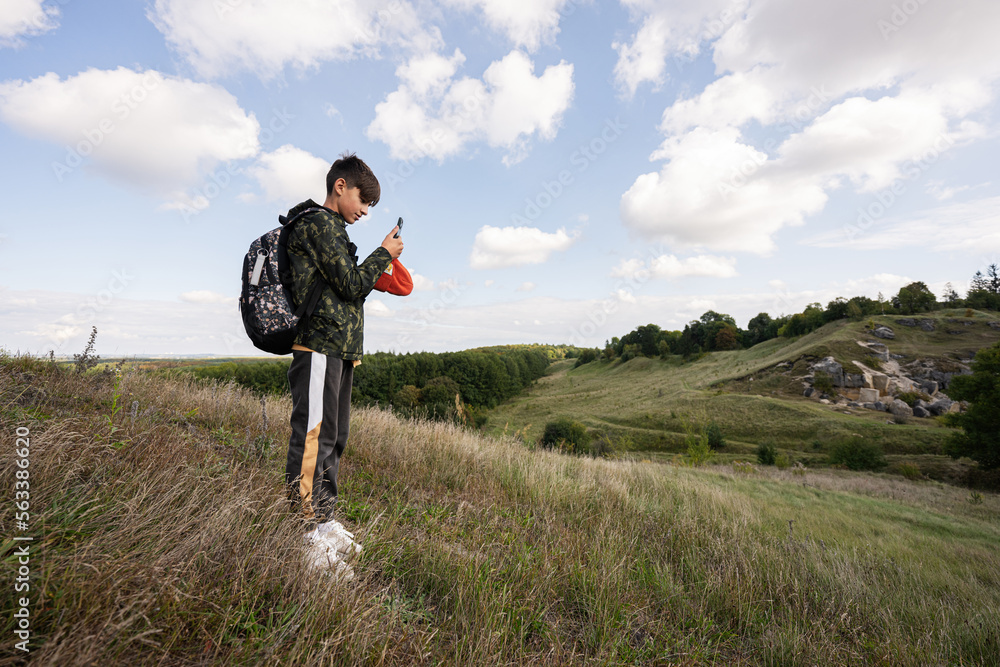 Activity on sunny autumn day, boy exploring nature. Kid wear backpack hiking and making photo on phone. Activity on sunny autumn day, boy exploring nature. Kid wear backpack hiking and making photo on phone.
