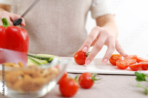 Beautiful young woman preparing vegetable salad in the kitchen. Healthy food. Vegan salad Diet concept. Healthy lifestyle. Cook at home. Prepare food close-up, only hands, olives, tomato, cucumber