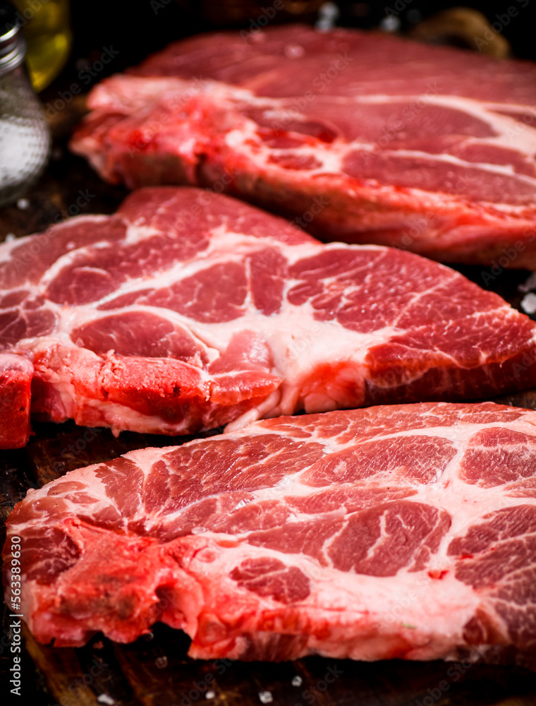 Raw pork steak on a wooden cutting board. Raw pork steak on a wooden cutting board.