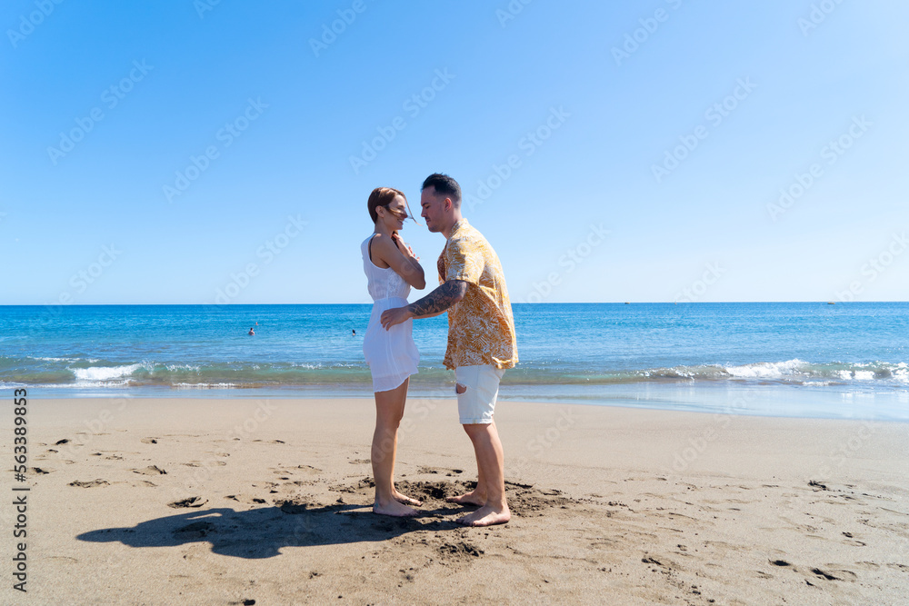 Happy young couple at the sea vacations, man and woman walking at the sea shore, vacations and honeymoon concept Happy young couple at the sea vacations, man and woman walking at the sea shore, vacations and honeymoon concept