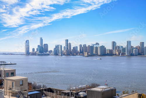 View of Jersey City skyline from lower Manhattan, sunny, blue sky, light clouds, nobody