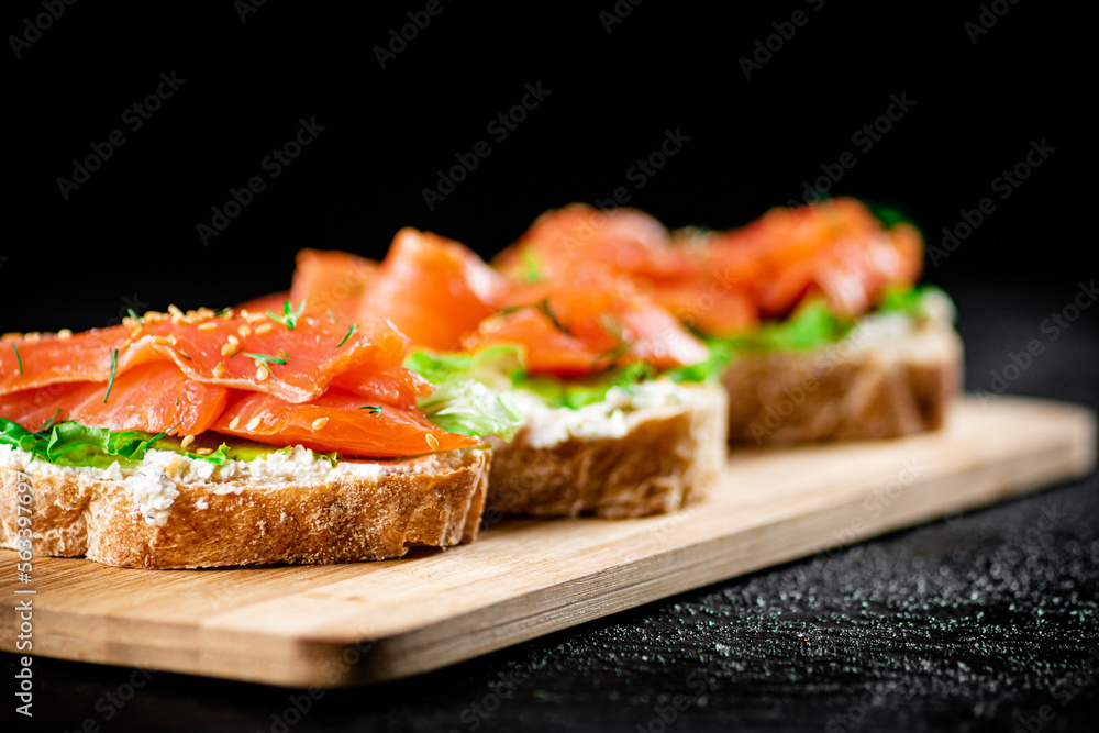 Sandwich with pieces of salmon on a cutting board. Sandwich with pieces of salmon on a cutting board.
