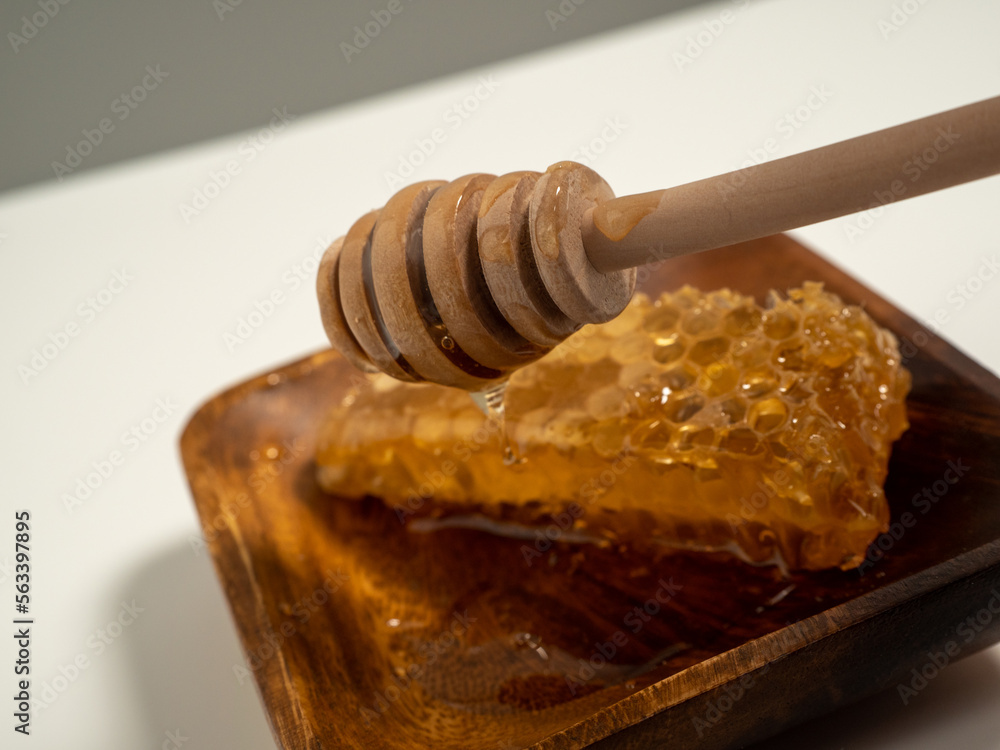 With honeycombs and a wooden spoon for honey in a wooden cup. Honeycombs and honey. With honeycombs and a wooden spoon for honey in a wooden cup. Honeycombs and honey.