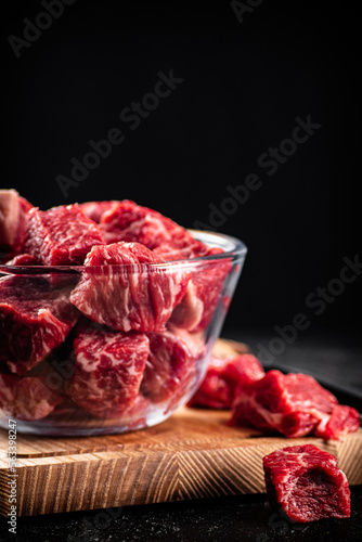 Raw sliced beef in a bowl on a cutting board. 