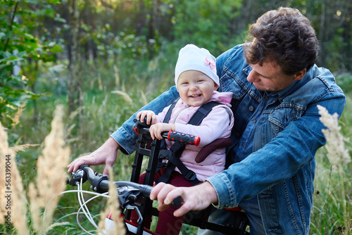 child and his father ride a bicycle using a child seat. The concept of family, and joint recreation.