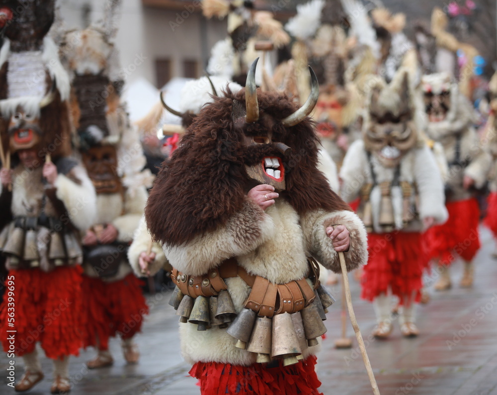 Breznik, Bulgaria - January 21, 2023: Unidentified people with traditional Kukeri costume are seen at the Festival of the Masquerade Games Surova in Breznik, Bulgaria