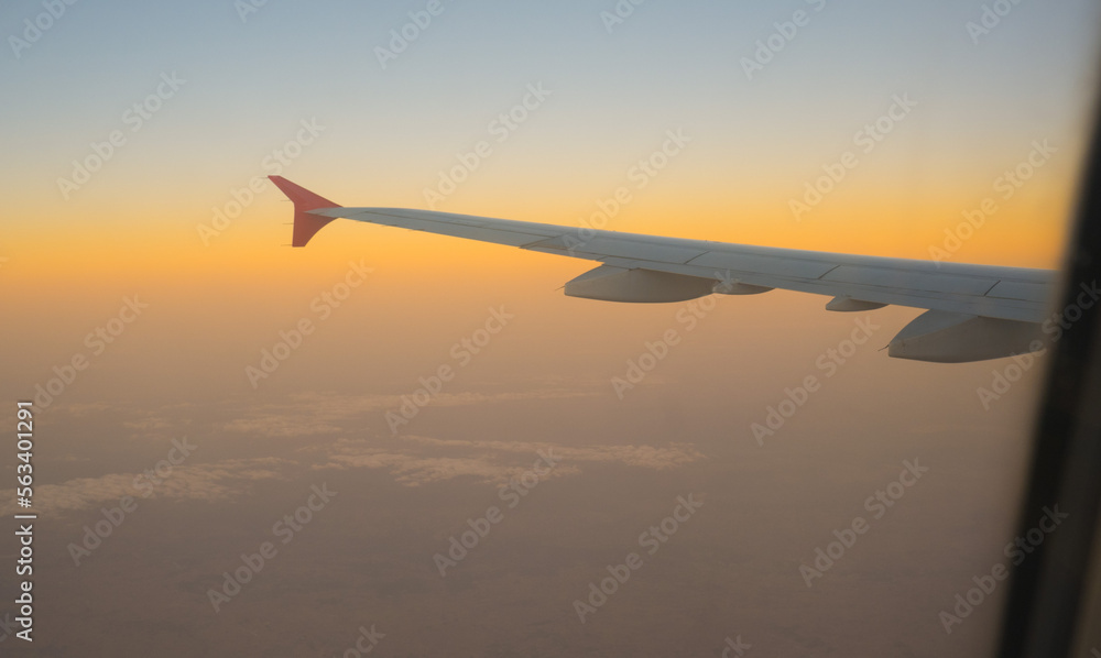 view of the sunset sky from the height of the flight above the clouds from the window of the aircraft. part of an airplane wing in the frame view of the sunset sky from the height of the flight above the clouds from the window of the aircraft. part of an airplane wing in the frame