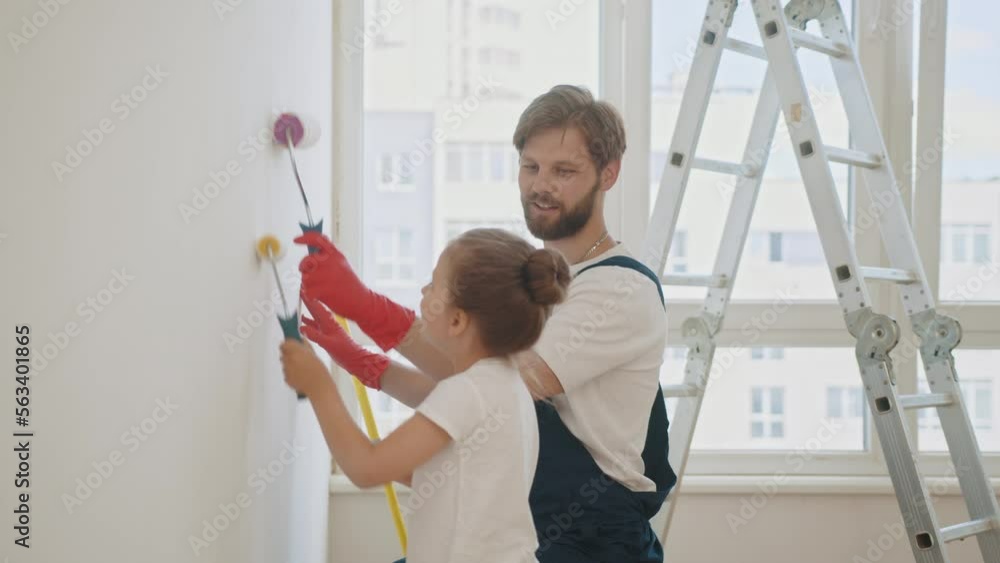 Father and his little daughter painting a wall in new home. Happy ...
