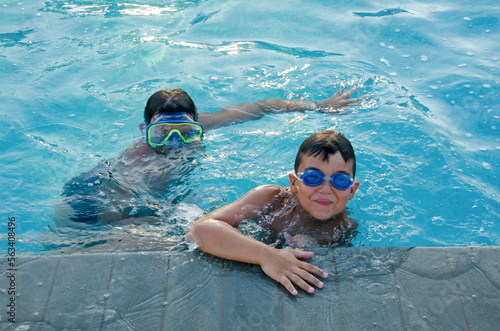 two little boys with underwater goggles in swimming pool