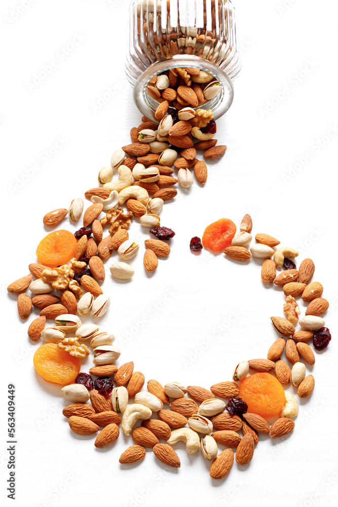 Obraz premium Dried fruits and nuts mixed and glass jar. Concept of the Jewish holiday Tu Bishvat on white background with copy space