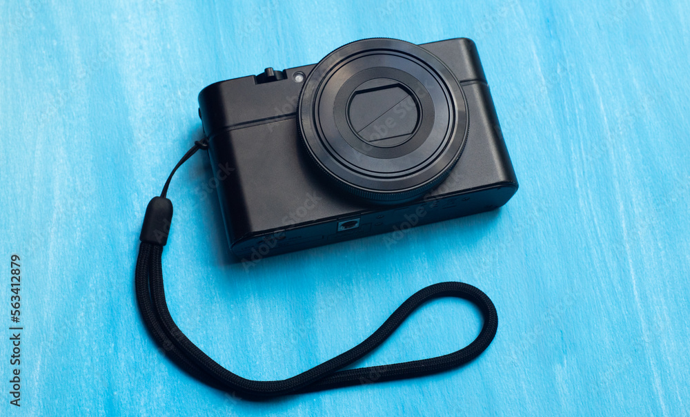 Compact camera on a blue background. The digital camera is black. A camera for street photography. Compact camera on a blue background. The digital camera is black. A camera for street photography.