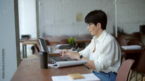 Attractive mature businesswoman working on laptop in office or coworking