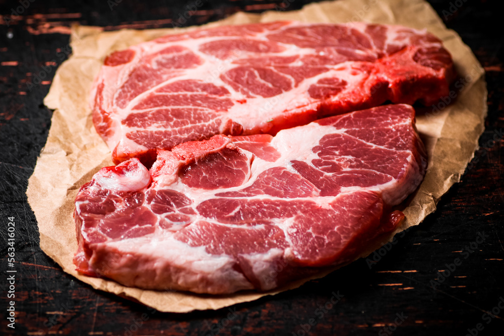 Raw pork steak on paper on the table. 