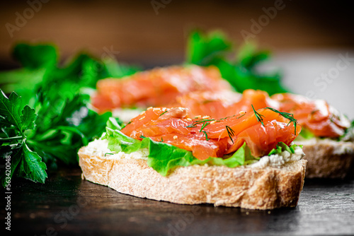 Sandwich with pieces of salmon and greens. 