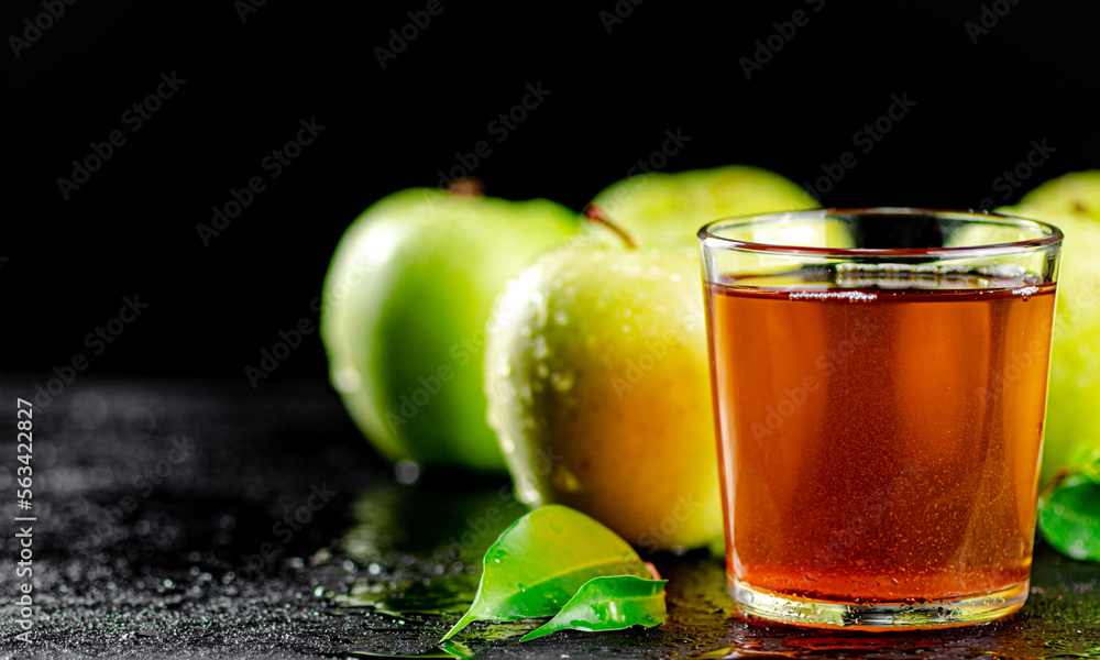 A glass of green apple juice with leaves on the table. A glass of green apple juice with leaves on the table.