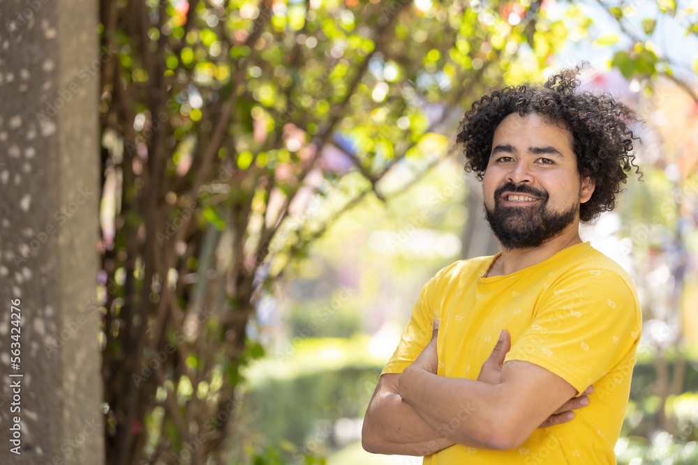 portrait of a Mexican man smiling with curly hair and beard arms crossed copy space portrait of a Mexican man smiling with curly hair and beard arms crossed copy space