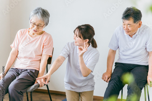 介護施設で椅子体操・運動・リハビリするシニア・高齢者の男女と理学療法士・介護士・トレーナー（脚）
 photo