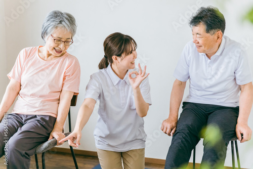 Fotografia, Obraz 介護施設で椅子体操・運動・リハビリするシニア・高齢者の男女と理学療法士・介護士・トレーナー