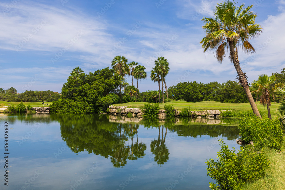 Beautiful view of blue water surface of pond with golf courses against blue sky with white clouds. Aruba. Beautiful view of blue water surface of pond with golf courses against blue sky with white clouds. Aruba.