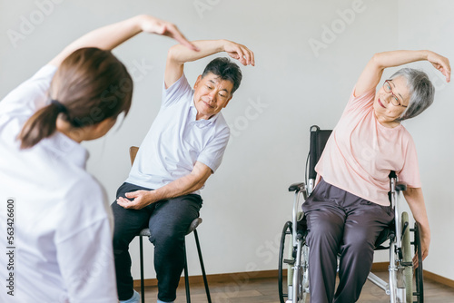 介護施設でボール体操・運動・リハビリするシニア・高齢者の男女と健康チェックするスタッフ