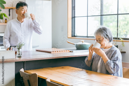 家のキッチンでコーヒーをいれる高齢者女性と高齢者男性（老夫婦）