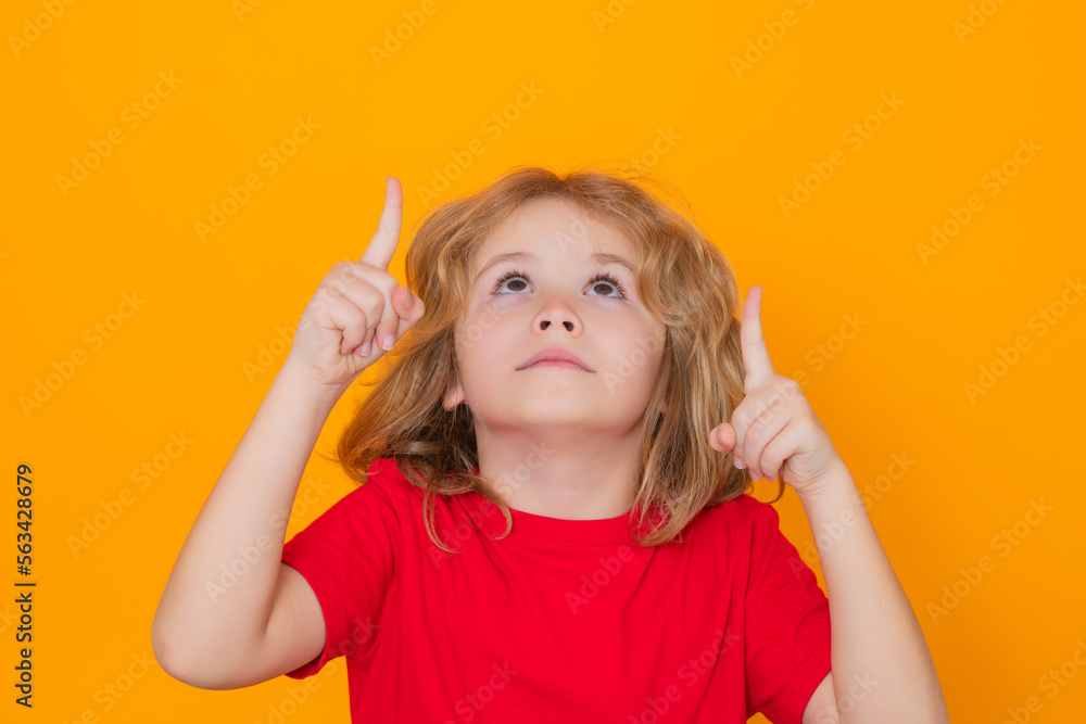 Portrait of kid pointing up finger on yellow background. Child pointing to copyspace, showing promo offers, points up. Portrait of kid pointing up finger on yellow background. Child pointing to copyspace, showing promo offers, points up.