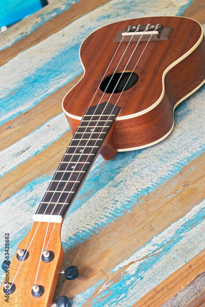 Fototapeta premium Ukulele, a small Hawaiian guitar, on rustic board