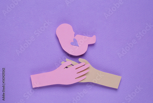 Woman`s health. Hands with newborn paper figures on lilac background, flat lay