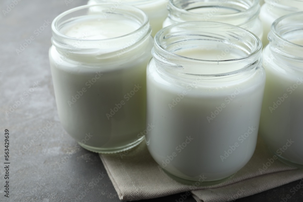 Tasty yogurt in glass jars on grey table, closeup Tasty yogurt in glass jars on grey table, closeup