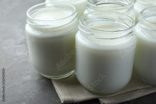 Tasty yogurt in glass jars on grey table  closeup