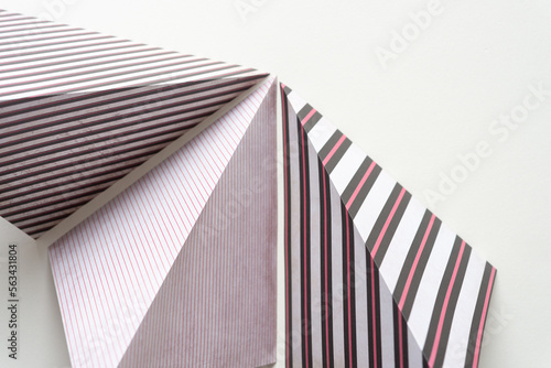 three folded scrapbook paper squares with mostly striped decorative patterns (standing) on blank paper