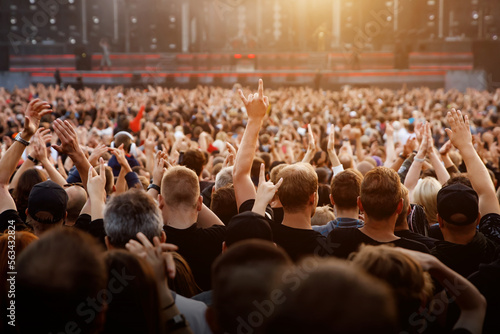 People with raised hands enjoy music concert.