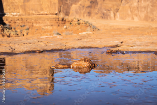 A lone rock in the middle of a small frozen puddle of water.