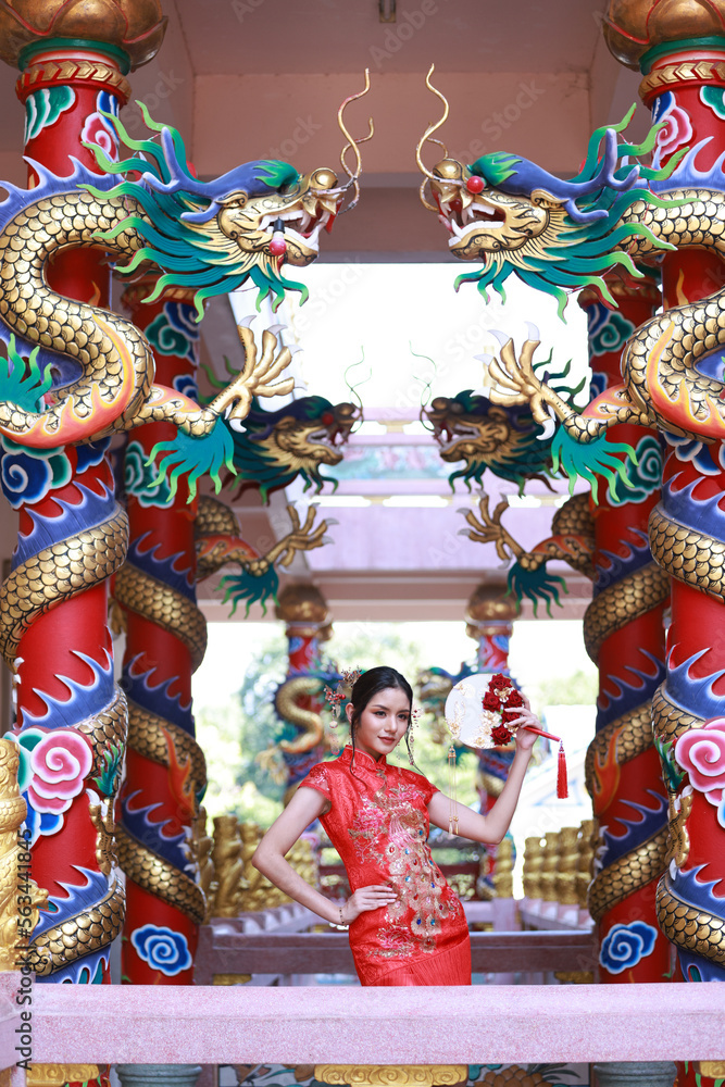 Fototapeta premium Portrait attractive Asian woman wearing traditional red cheongsam qipao dress in Naja Chinese shrine at Chonburi of Thailand, Chinese new year concept