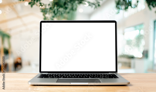 Fotografia Laptop blank screen on wood table with blurred coffee shop cafe interior backgro
