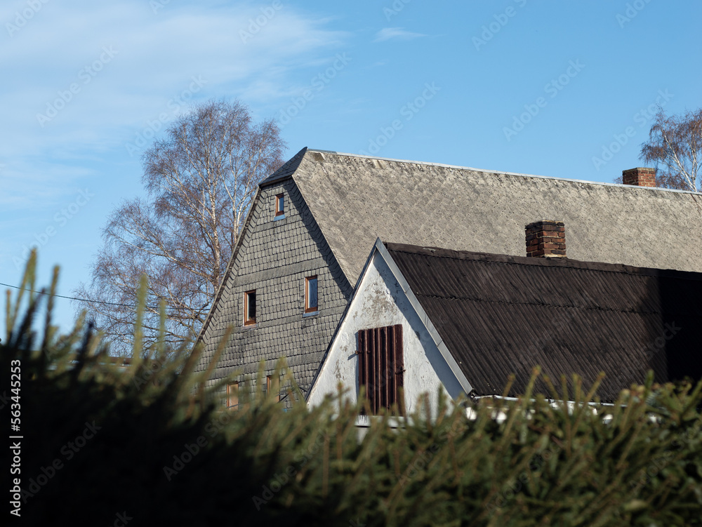 Old house with asbestos sheets on the exterior wall and on the roof. The weathered cement plates with fibres are forbidden in Germany and expensive to dispose. Old house with asbestos sheets on the exterior wall and on the roof. The weathered cement plates with fibres are forbidden in Germany and expensive to dispose.