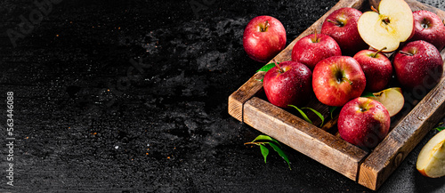 Pieces and whole red apples on a wooden tray. 