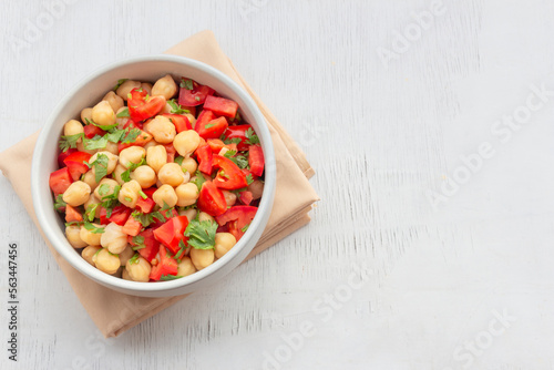 Healthy food chickpeas salad add tomato coriander in white bowl on wood background.