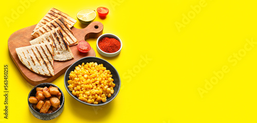 Board with tasty quesadillas and ingredients on yellow background with space for text