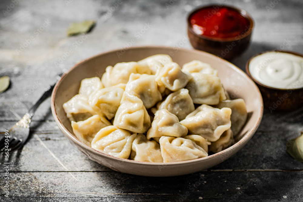 Dumplings in a plate with tomato sauce and sour cream. 