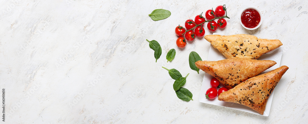 Plate with tasty Uzbek samsas, sauce and tomatoes on light background with space for text Plate with tasty Uzbek samsas, sauce and tomatoes on light background with space for text