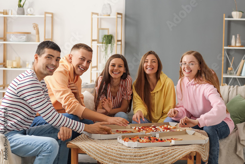 Group of friends with pizza spending time together in living room