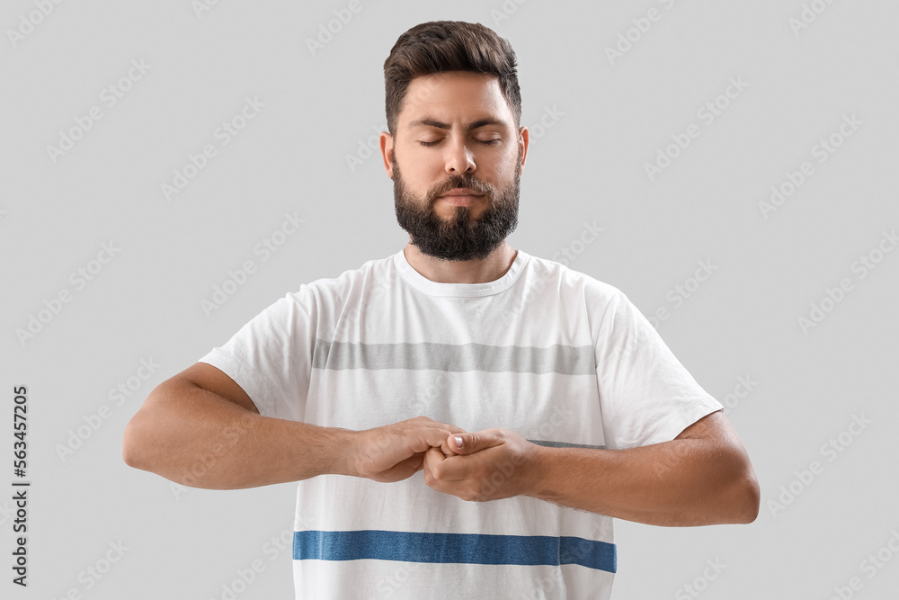 Handsome young man meditating on light background Handsome young man meditating on light background