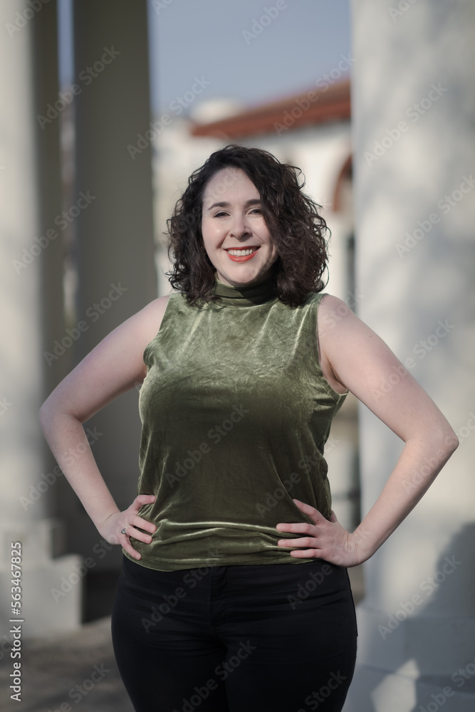 A woman with pale skin and black, wavy hair poses confidently outdoors. A woman with pale skin and black, wavy hair poses confidently outdoors.
