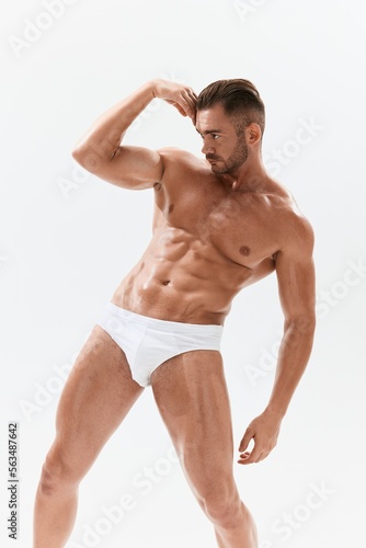 Man athletic body bodybuilder in briefs with naked torso abs full-length in the background  fitness classes. Advertising  sports  active lifestyle  competition  challenge concept.