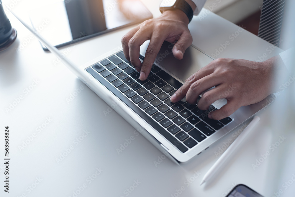 Businessman working on laptop computer on white table at office. Business man hands typing on laptop, online working, surfing the internet, close up Businessman working on laptop computer on white table at office. Business man hands typing on laptop, online working, surfing the internet, close up